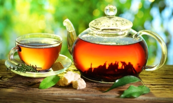 Cup of tea and teapot on a blurred background of nature.